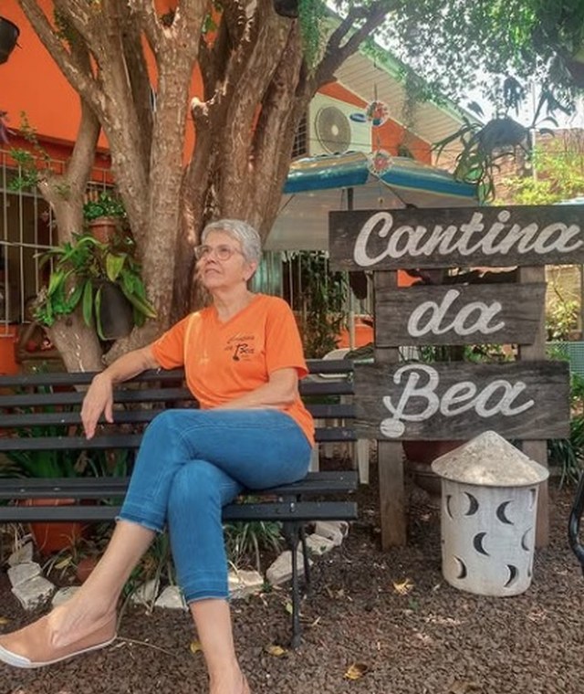 Bea sentada no banco da Cantina da Bea